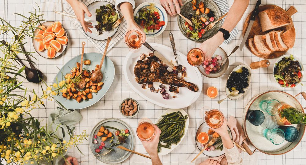 Flat-lay of peoples hands with glasses of rose wine over table