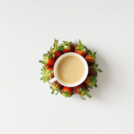 Coffee and saucer surrounded with strawberries