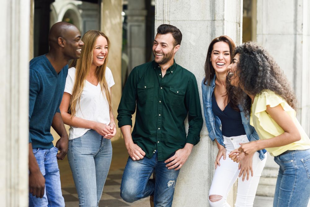Group of women and men chatting together by city pillar
