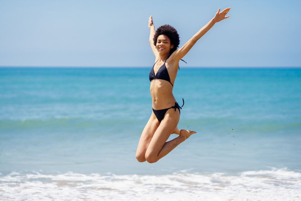 Woman jumping for joy in bikini at beach