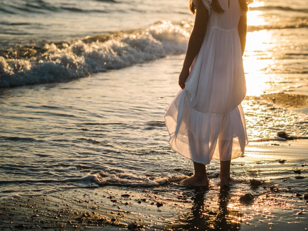 Adorable girl walking on seaside at sunset