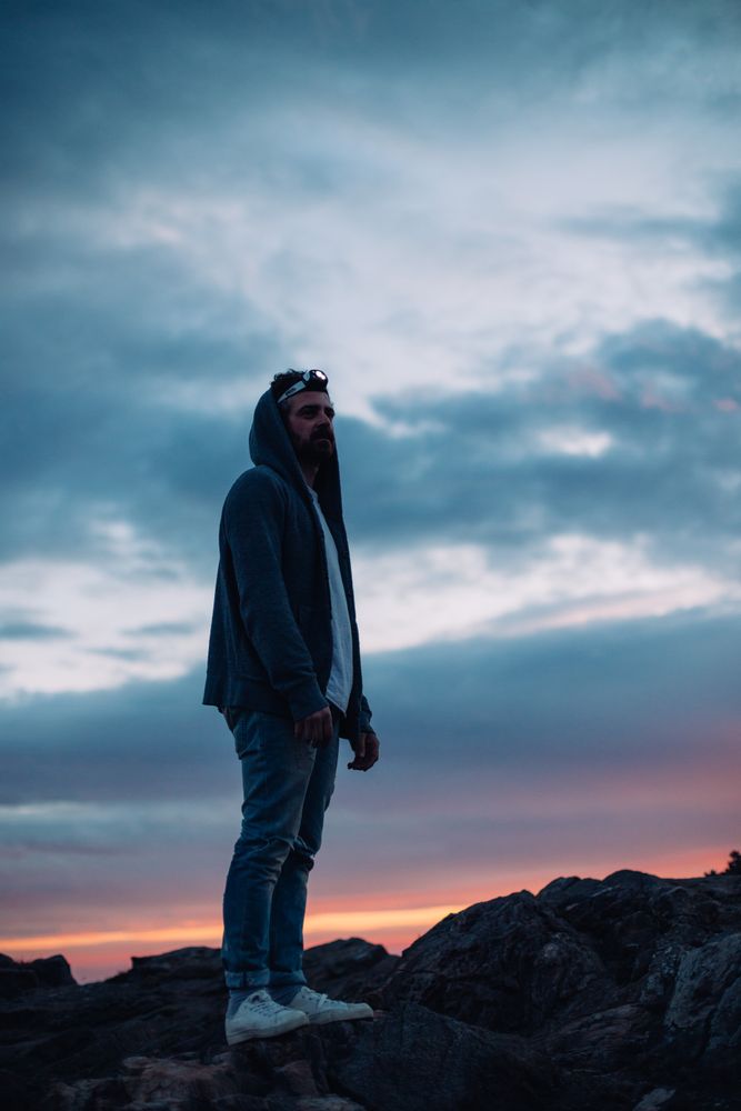 Man on cliff at sunset wearing a headlamp