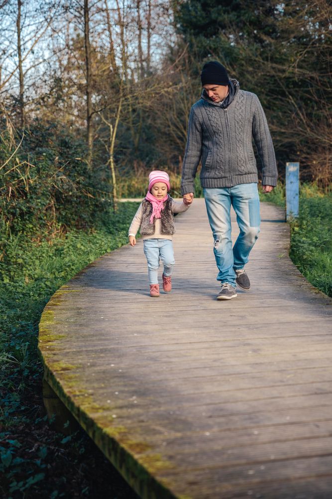 Father in fall coats walking with daughter in forest