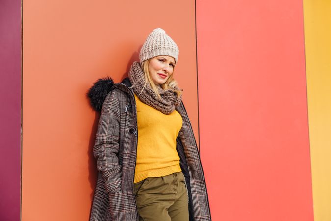 Blonde woman leaning on a colorful wall