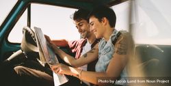 Smiling couple looking at map sitting in truck on road trip 0yl8Gb