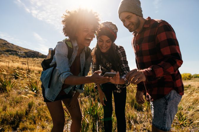 Group of hikers looking at pictures on mobile phone and laughing