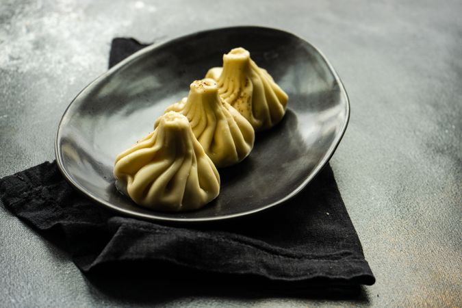 Plate of three Georgian khinkali dumplings on kitchen counter