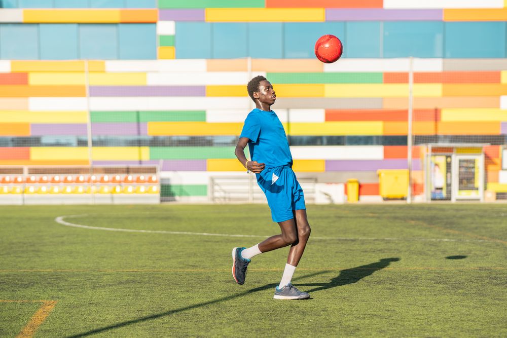 Black teenager juggling football ball