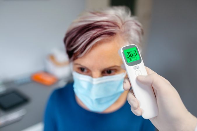 Older woman without fever whose temperature is taken with an infrared thermometer