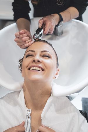 Stylist washing hairs to young woman