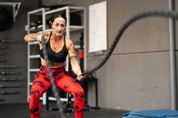 Woman working out upper body with rope in gym