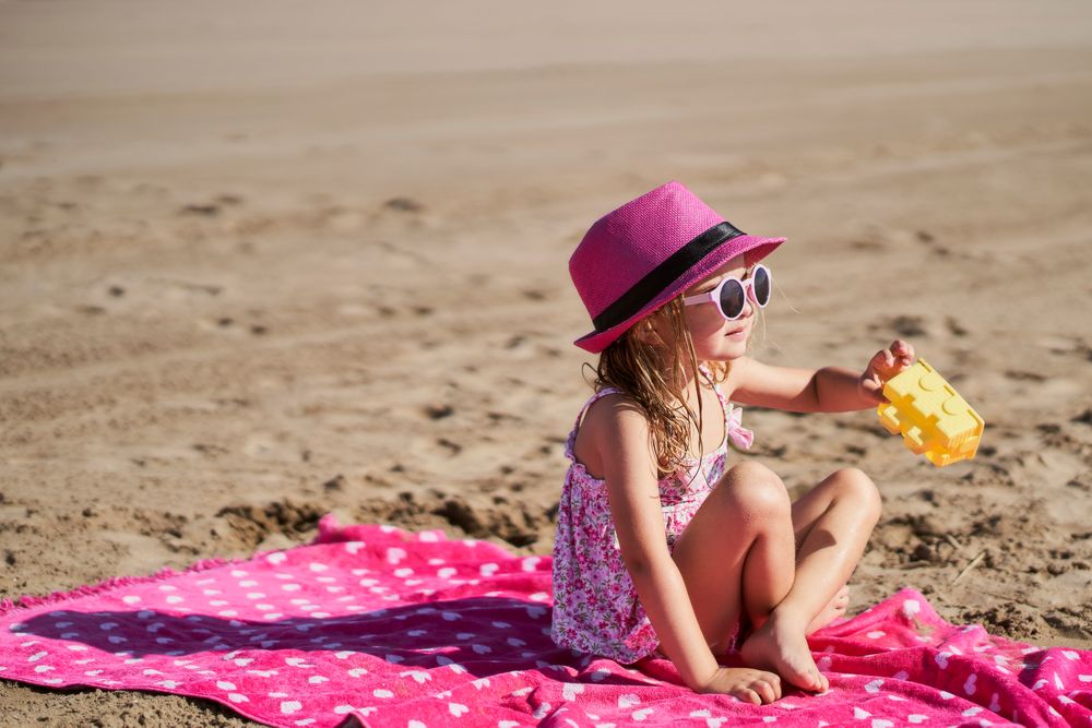 portrait of a little girl with cap and sunglasses at the beach
