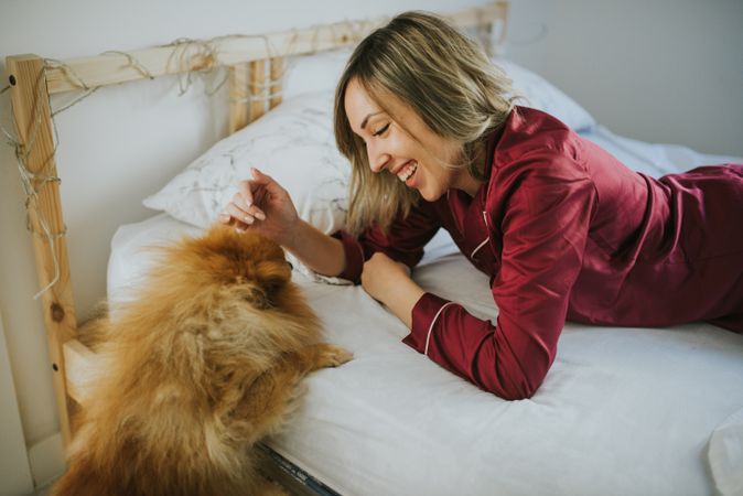 Smiling woman lying in bed with dog