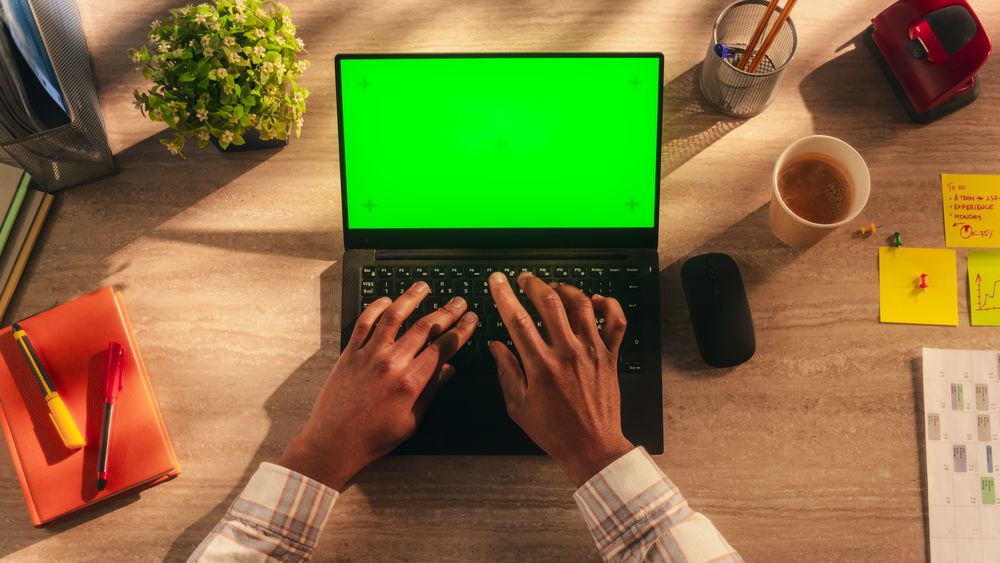 Anonymous African Manager Typing on a Laptop with Mock Up Green Screen Chromakey Display. Businessman Using Computer, Working on Corporate Partnership Project Plan. Top Down View