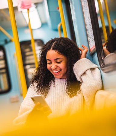 Smiling Black woman using smartphone in transport