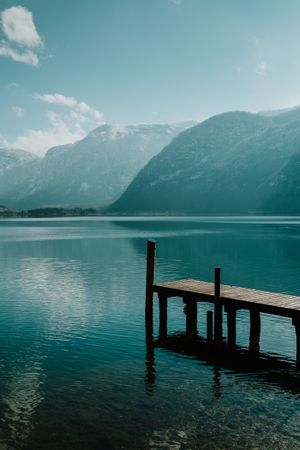 Lonely empty pier in turquoise water along mountain