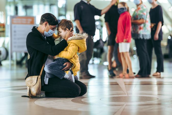 Woman and her boy sitting on floor at airport