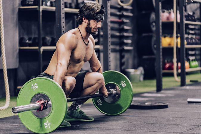 strong and athletic man doing barbell workout in modern gym