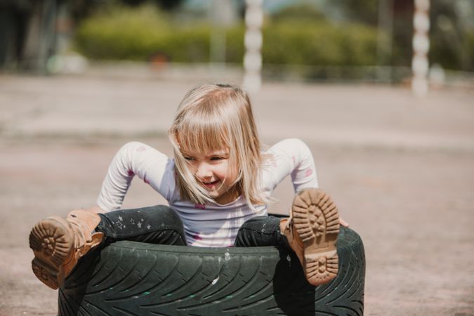 Little girl sitting inside tire