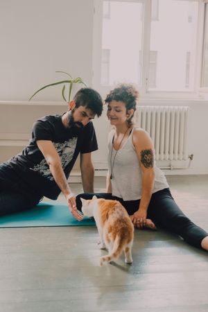 Loving couple cuddling on floor while cat walking around