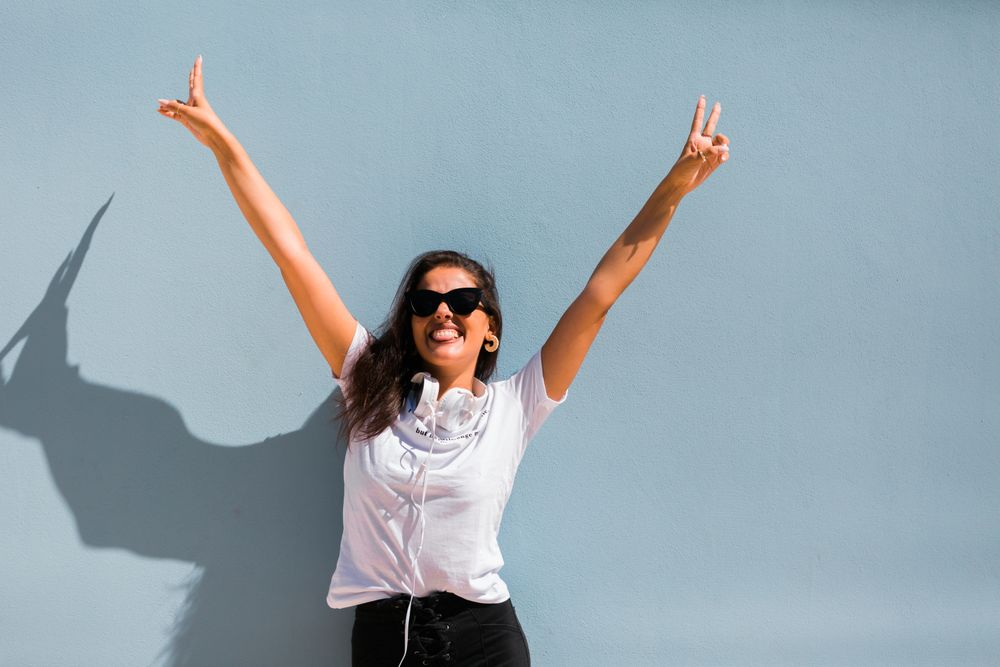 Cheerful casual woman in sunglasses standing on city street