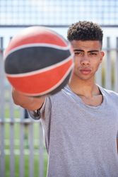 Latino man holding basketball at arm length