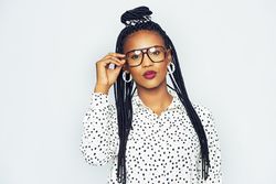 Studio portrait of confident woman with a serious expression adjusting her glasses