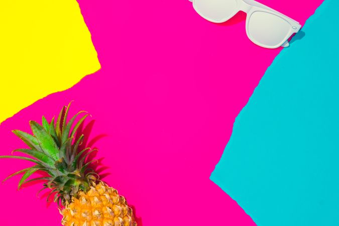 Pineapple and sunglasses on pattern of ripped paper in vivid colors