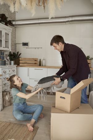 Cheerful couple unpacking boxes in light kitchen
