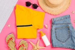 Sea vacation accessories on yellow background, top view