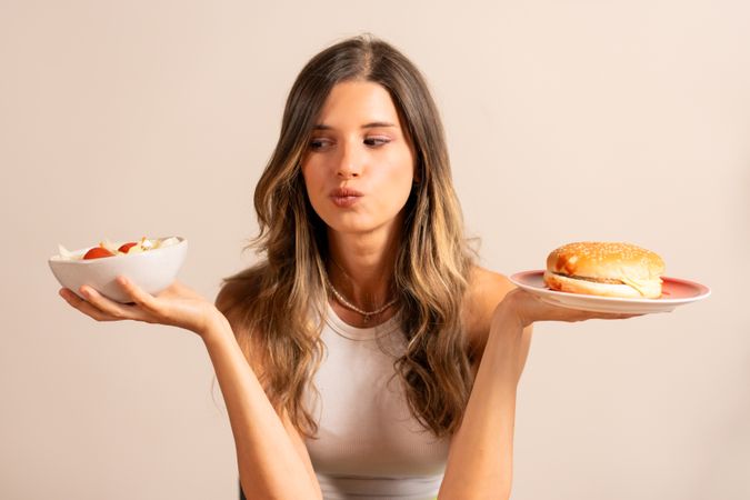 Woman Choosing Between Healthy Salad and Unhealthy Burger - Nutrition Decision