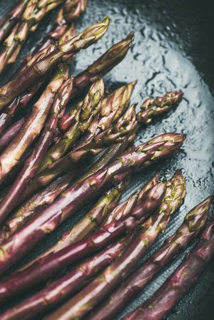 Close up of purple asparagus against blue background, vertical composition