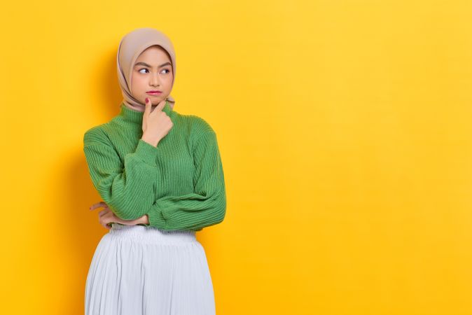 Woman in headscarf pondering something with hand on her chin