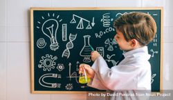 Boy dressed as chemist pointing at chalkboard 0gX7VX