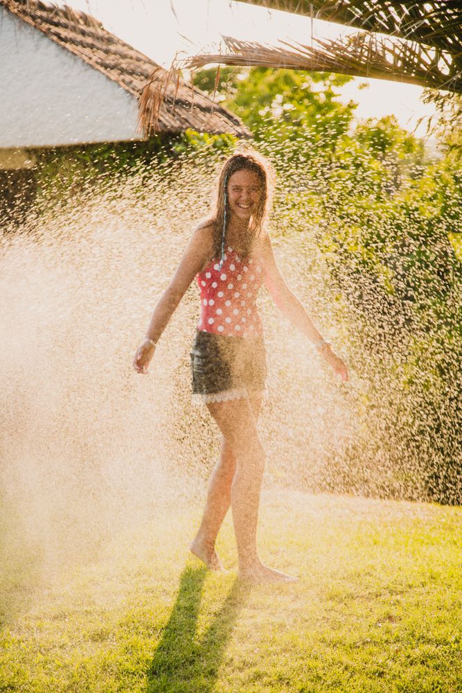 Cheerful teenager having fun with jet of water