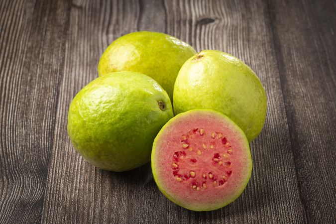 Fresh sliced guavas on wooden table.