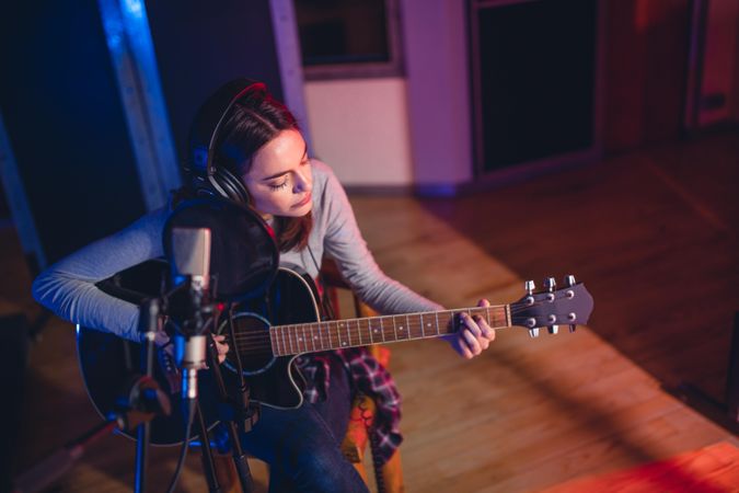 Woman artist playing guitar in a recording studio