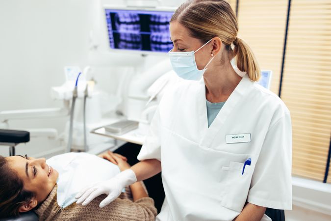 Female dentist sitting by a woman patient and discussing treatments