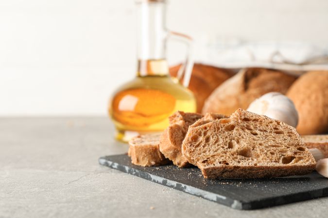Composition with bakery products, garlic and olive oil on grey background, closeup and space for text