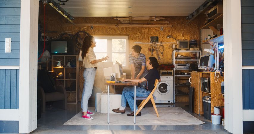 Diverse Team Of Three Young Tech Startup Company Founders Working In Retro Garage, Using Old Desktop Computer.