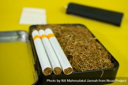 Close up of cigarettes resting on box of loose leaf tobacco 0yXz3L