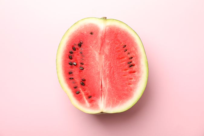 Half of fresh watermelon on pink background. Summer fruit