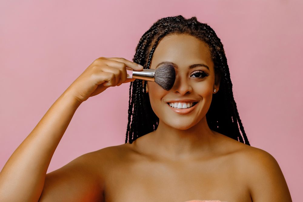 Black woman holding make up brush over her eye