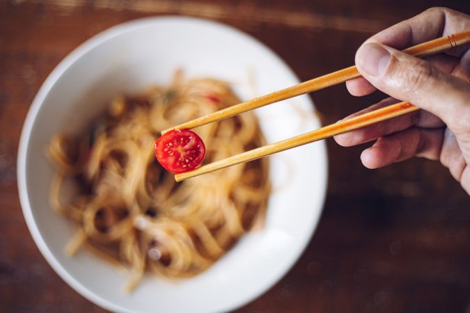 Faceless person eating dinner with chopsticks