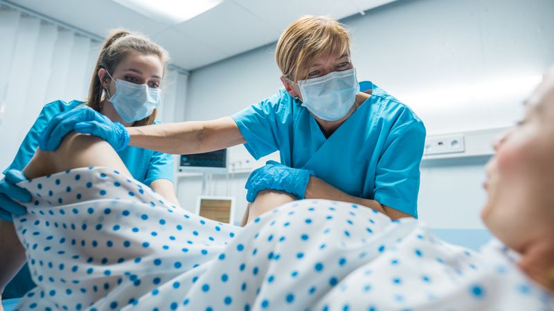 In the Hospital Professional Midwives Helping Spread Legs to Woman to Give Birth