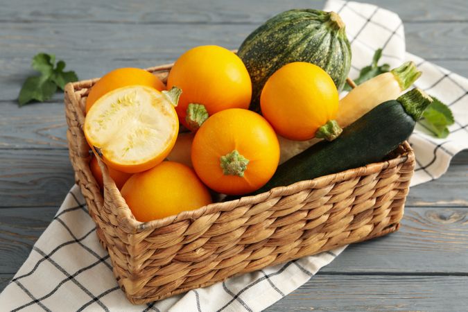 Basket with zucchini on napkin on wooden table