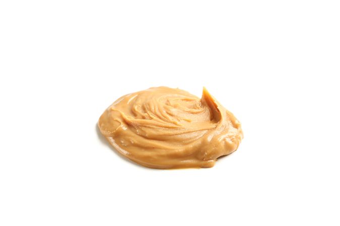 Creamy peanut butter isolated on light background. A traditional product of American cuisine