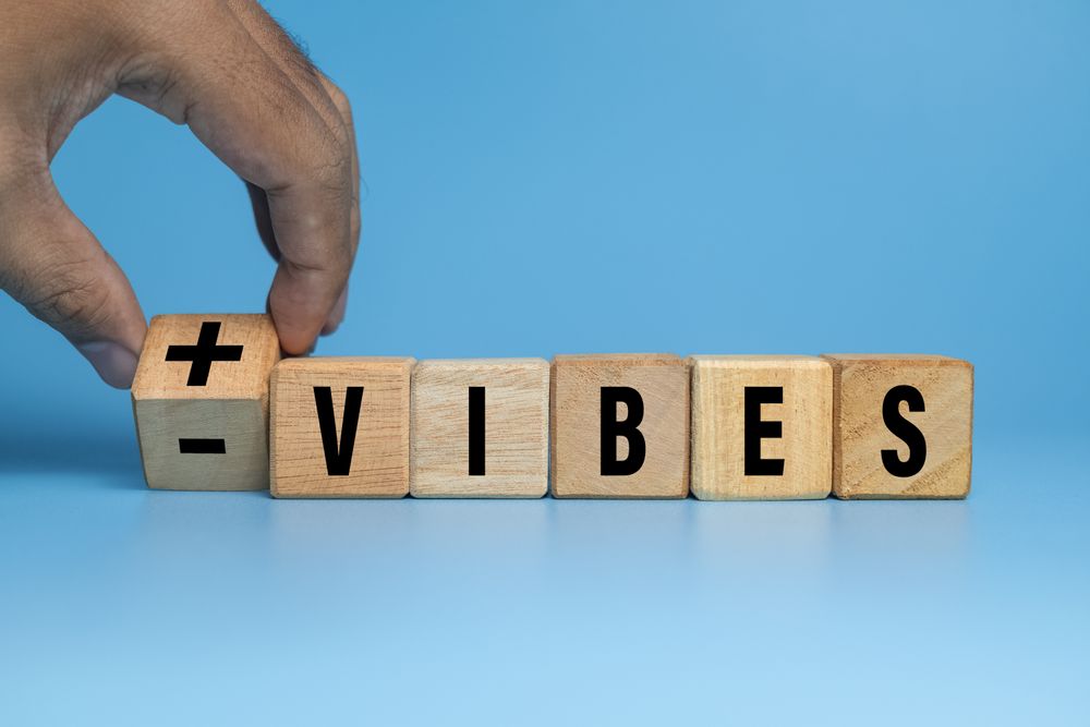 male hand flip wooden blocks with positive and negative vibes isolated on blue background