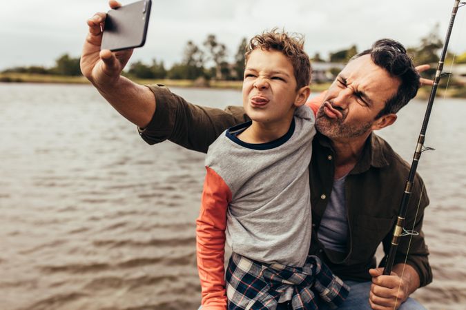 Playful father and son taking a selfie making silly faces