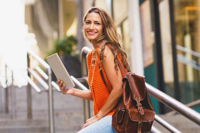 Woman on street smiling with digital tablet
